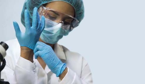 A researcher putting latex gloves at a laboratory, preparing for research